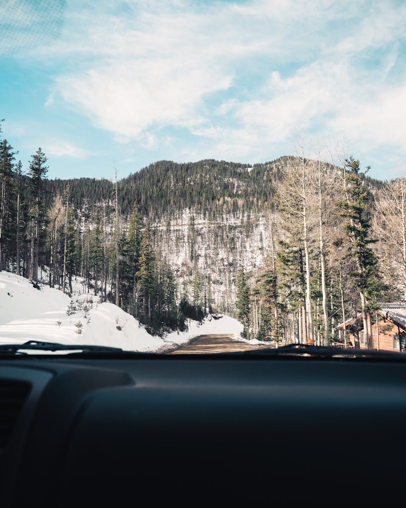Scenic winter view of snowy Taos mountain road through car windshield.